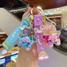 a person holding several key chains in their hand with charms attached to the handles and sides