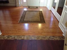 a living room with hard wood flooring and white trim on the door way to another room