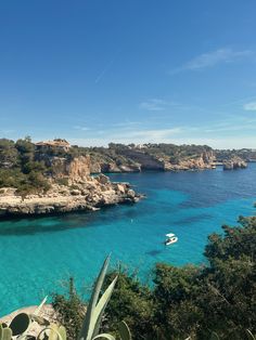 the water is crystal blue and there are boats on it in the bay near some cliffs