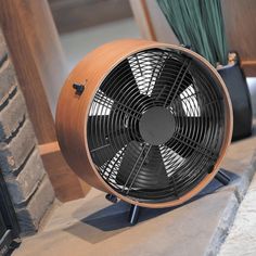 a fan sitting on top of a table next to a window