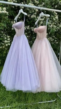 two dresses hanging on a clothes line in front of some white and pink flowers at the same time