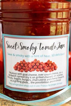 a jar of sweet smoky tomato jam sitting on top of a wooden table next to apples