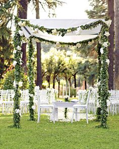 an outdoor wedding setup with white chairs and greenery