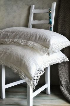 three white pillows stacked on top of each other in front of a gray wall and wooden floor