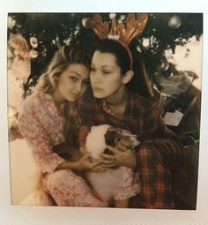 two young women are hugging each other in front of a christmas tree with reindeer antlers on their head