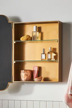 an open wooden medicine cabinet next to a mirror and towel rack with bottles on it