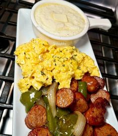 a white plate topped with breakfast food next to a bowl of soup and potatoes on top of a stove