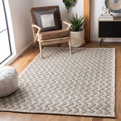 a living room area with a chair, rug and potted plant on the floor