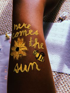 someone has painted the words bee comes to the sun on their arm and back with yellow flowers