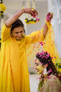 two women dressed in yellow are throwing petals at each other