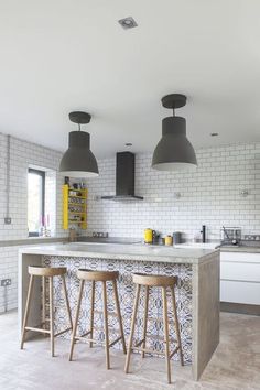 a kitchen with two bar stools next to an island in the middle of it