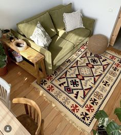 a green couch sitting on top of a hard wood floor next to a wooden table