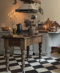 a kitchen with an old fashioned table and black and white checkerboard flooring