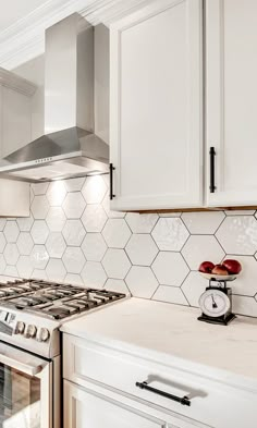 a stove top oven sitting inside of a kitchen next to white cabinets and counter tops