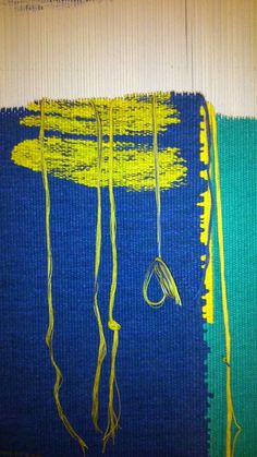 an abstract painting with yellow and blue colors on the bottom half of it, hanging from strings