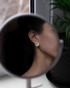 a woman's reflection in a mirror next to a potted plant and window