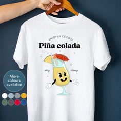 "Looking for a cool t-shirt for yourself or a gift for your best friend? Our \"Enjoy an iced cold pina colada\" retro inspired cocktail tee is perfect for parties, birthdays, or just because it's Tuesday. Grab your t-shirt today and let your unique style shine! HOW TO ORDER 1. Chose shirt colour Select from the drop down menu 2. Select shirt size See our size guide for details in the listings images 3. Add to cart Purchase your lovely new shirt SIZING AND COLOURS We offer inclusive sizing with our shirts, ranging from S-3XL. See our size guide for details in the listings images. We only offer colours that we know our designs will look great on. See our colour guide for options for this design in the listings images. PRODUCT DESCRIPTION A classic fit unisex t-shirt with a relaxed style for Trendy Custom Print T-shirt Gift, Casual Party T-shirt With Custom Print, Trendy Graphic Print T-shirt For Gift, Casual Custom Print T-shirt For Party, Trendy Screen Print T-shirt For Gifts, Trendy Summer T-shirt As Gift, Casual Graphic Print T-shirt For Party, Trendy Summer T-shirt For Gifting, Casual Cartoon Print T-shirt For Gifting