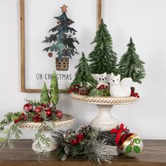 three christmas trees are sitting on top of a cake platter with other holiday decorations