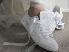 a bride's white sneakers are tied up on the floor