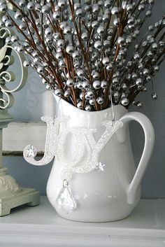 a white vase filled with lots of silver balls