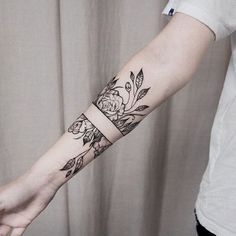 a woman's arm with two tattoos on it and flowers in the middle,