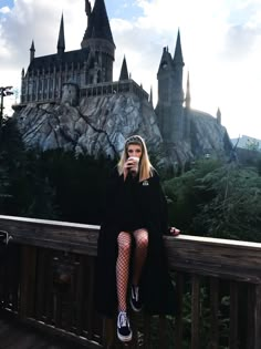 a woman sitting on top of a wooden deck next to a castle in the background