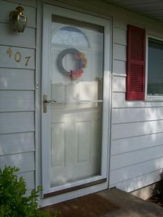 a white door with red shutters and a wreath on it