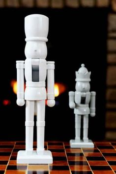 two white robot figurines sitting on top of a checkerboard table next to each other