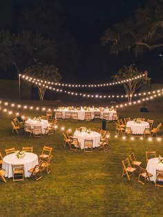 an outdoor dining area is lit up with string lights and white tablecloths set for dinner