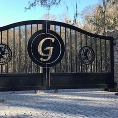 an iron gate with two lions on it and the letter g at the top is in front of a brick wall