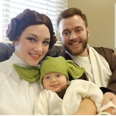 a man and woman are holding a baby wearing yoda costumes while smiling at the camera