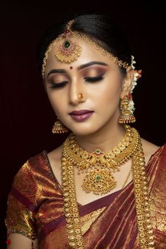 a woman wearing gold jewelry and makeup