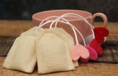 several small pieces of felt sitting on top of a wooden table next to a mug