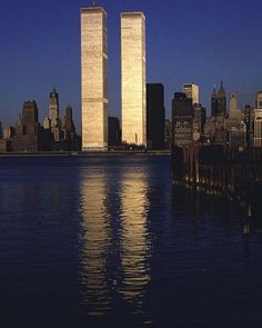 the twin towers are reflected in the water at night, with skyscrapers in the background