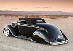 an old black car is parked in the desert