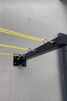 two yellow ropes are attached to the side of a gray wall with black metal brackets