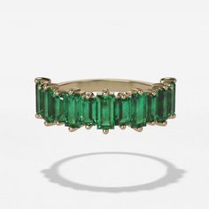 This is a stunning piece, perfect for adding style and flair to any look. Made using baguettes shaped emerald gemstones, it has a unique yet timeless aesthetic that will never go out of style. The halfway band design means this ring will wear comfortably and completely complement your existing jewelry collection. Whether it's worn on its own or stacked with other rings, this piece is sure to give you unforgettable color. The five millimeter width makes the ring just wide enough to be noticed wit Half Eternity Baguette Cut Emerald Jewelry, Baguette Cut Emerald Half Eternity Jewelry, Elegant Emerald Baguette Cut Ring, Luxury 14k Gold Emerald Ring With Baguette Diamonds, Elegant Emerald Ring With Baguette Diamonds, Baguette Cut Emerald Ring For May Birthstone, Luxury Emerald Half Eternity Jewelry, Emerald Cut Eternity Band, Baguette Wedding Band