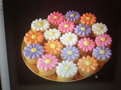 cupcakes decorated with colorful flowers on a gold plate