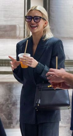 a woman in business attire holding a drink and pointing to another person's hand