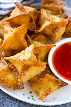 some fried food on a white plate with ketchup and dipping sauce in the background