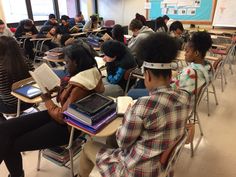 students sitting at desks in a classroom with laptops on their laps and one student reading