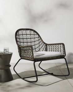 a wicker rocking chair next to a potted plant