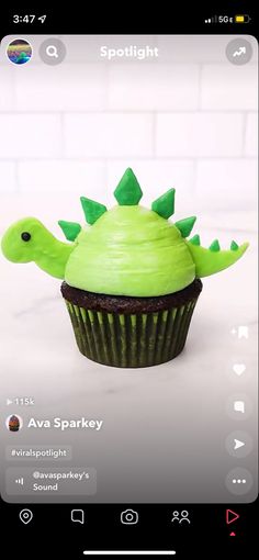 a cupcake with green frosting decorated like a dinosaur