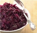 a bowl filled with red cabbage next to a spoon