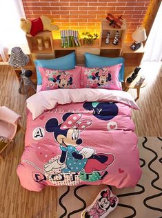 a bed with minnie mouse on it in a room next to a brick wall and wooden floor