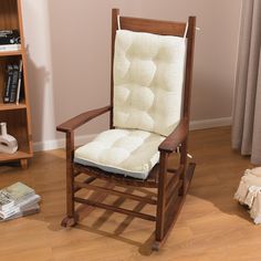 a wooden rocking chair with a cushion on top of it in front of a bookshelf