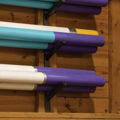 several different colored pens are lined up in a wooden box with black handles and blue, yellow, purple, and white ones