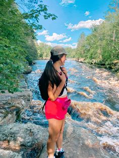 a woman is standing on the edge of a river