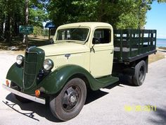 an old green truck is parked on the side of the road