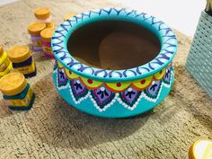 a blue pot sitting on top of a rug next to some yellow and purple jars